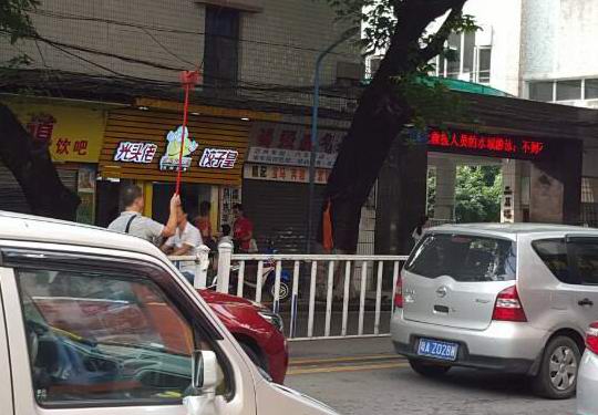 城市的温度:增城区荔城二小门口两男子撑起垂落电缆线 方便行经车辆